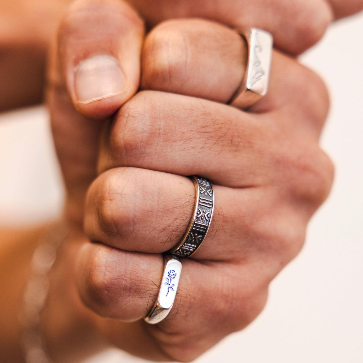 A close-up shot of a model's fist with multiple rings, including the ROSA I RING, highlighting the masculine and modern style of Billie Jo jewellery.