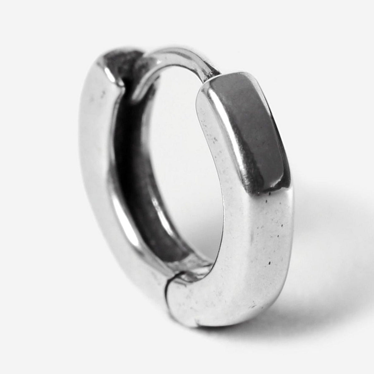 A single sterling silver Billie Jo Lumina hoop earring, showcasing its smooth, polished finish and minimalist design against a stark white background.