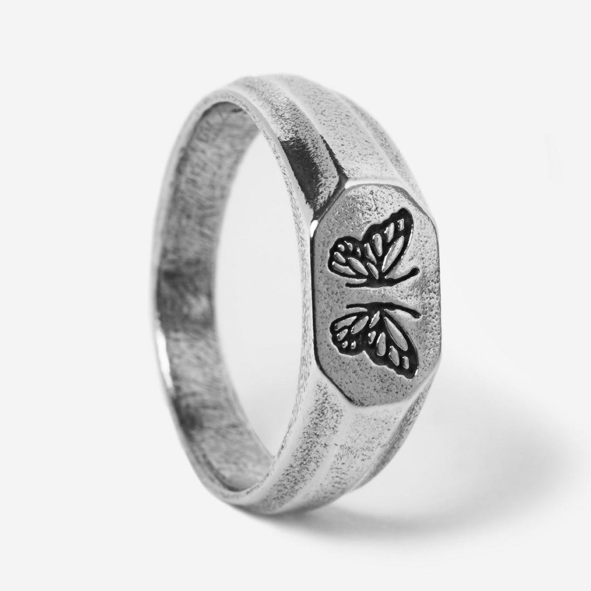 A studio shot of the sterling silver Revival Ring by Billie Jo. The ring has a flat, elongated face with two butterfly engravings and a textured, rustic finish.