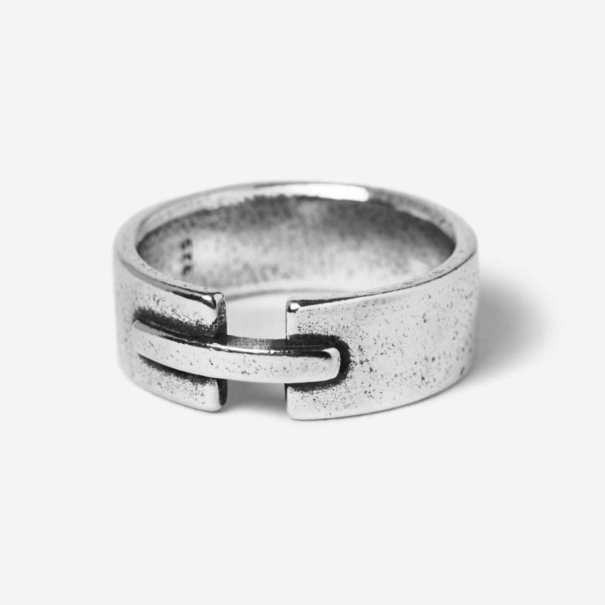 A studio shot of the Billie Jo Bind Ring in 925 sterling silver. The men's ring has a unique, industrial-inspired design with an interlocking clasp detail and a brushed, weathered finish.