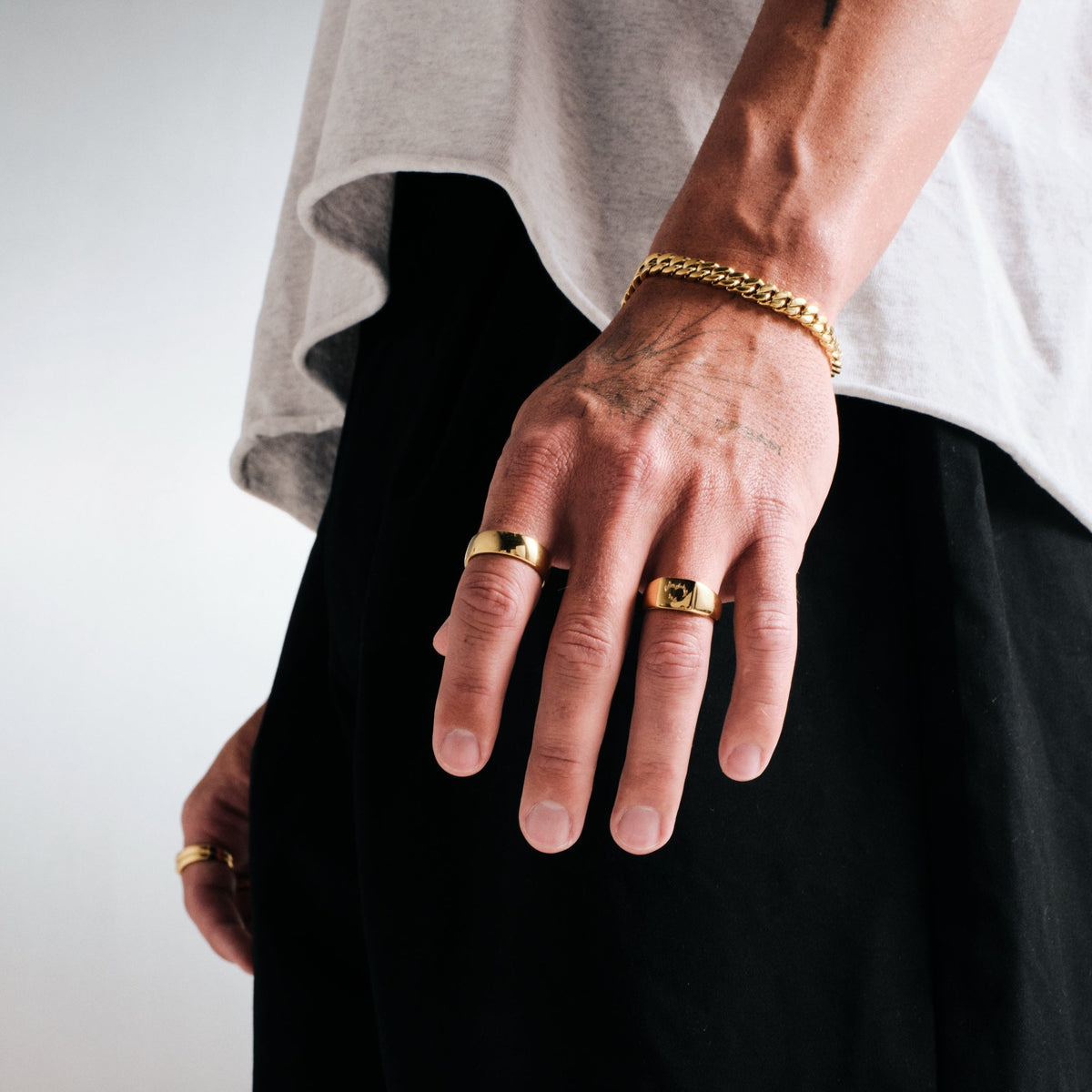 Men's Gold Ember Ring in 18k gold infused stainless steel, worn on his left ring finger, hand hanging by his side