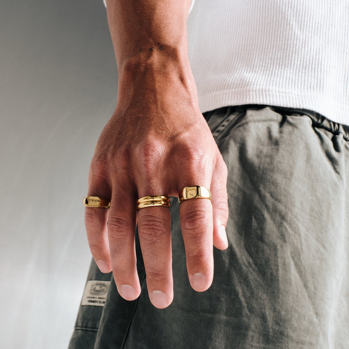 Men's Gold Ember Ring in 18k gold infused stainless steel, worn on his right index finger, hand hanging by his side