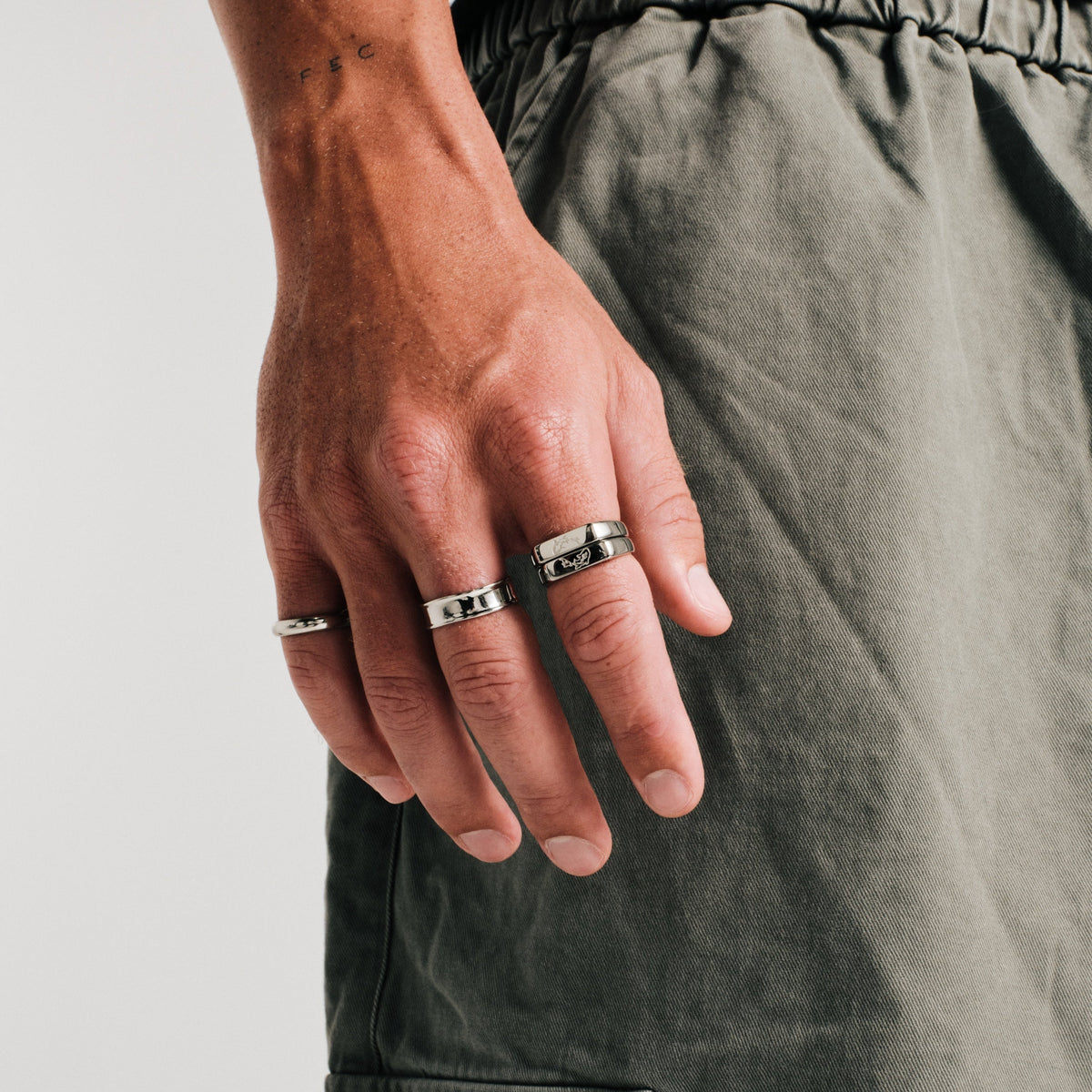 Men's Forge Ring in 316L stainless steel, silver finish, worn on the middle finger, hand by his side, olive pants