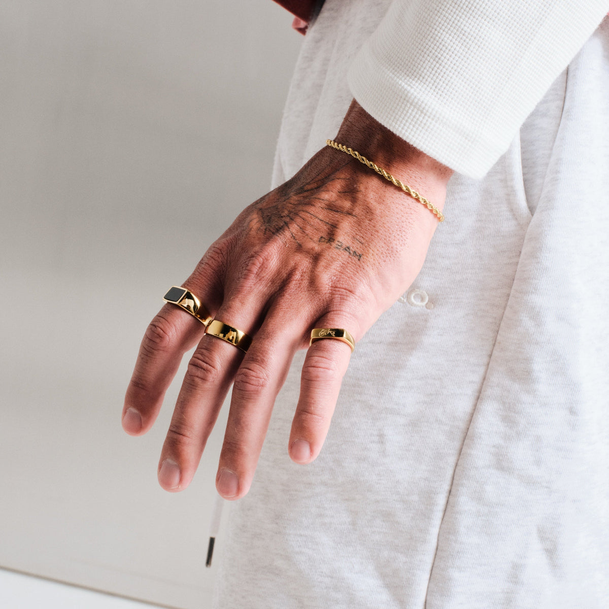 Men's Gold Onyx Ring in 18k gold infused stainless steel, worn on his left index finger, hand by his side, fingers spread