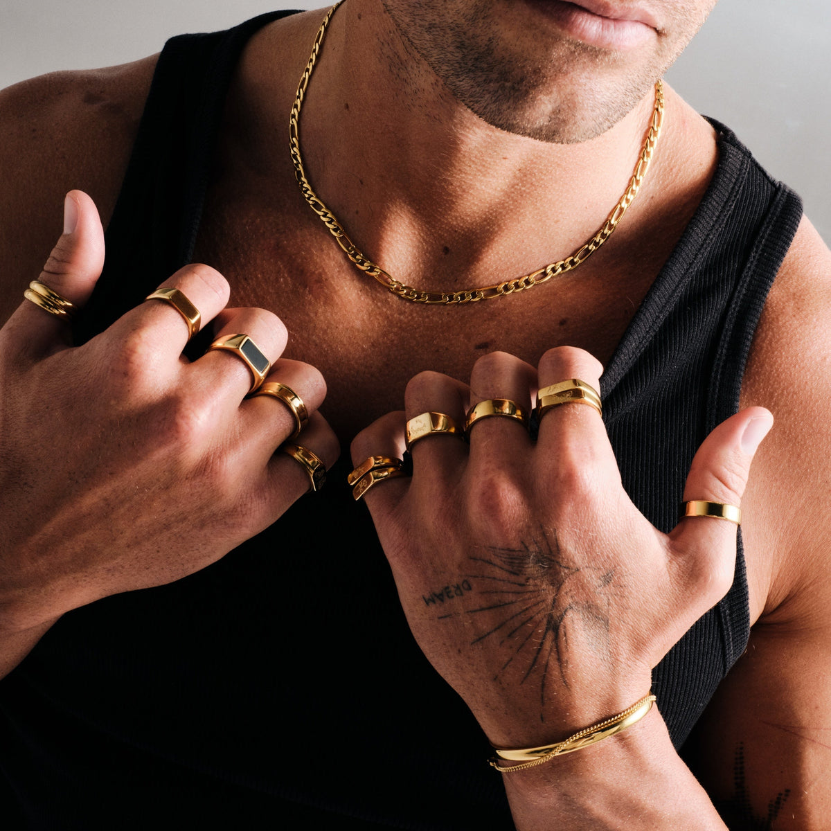 Men's Gold Serenity Ring in 18k gold infused stainless steel, worn on the thumb, hands at the neckline of his black singlet