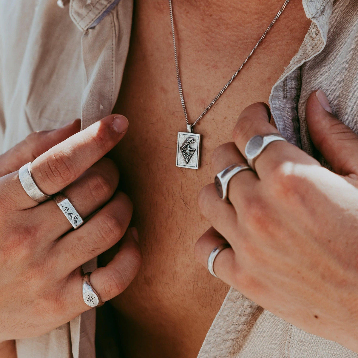 A man wearing the Burleigh Pendant from Australian jewellery brand Billie Jo, the silver necklace and pendant shown against his bare chest.