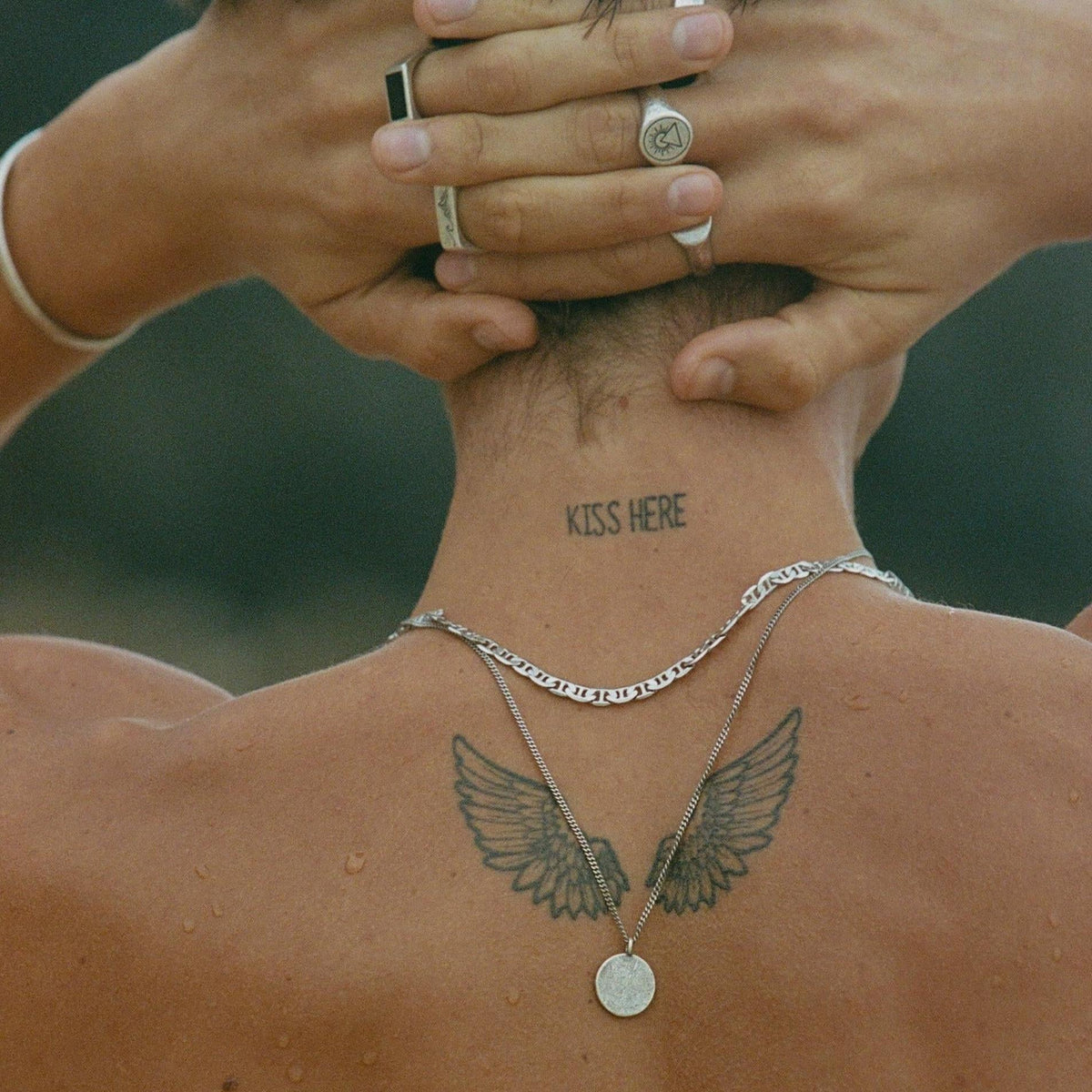 From behind, a man with tattoos wears the sterling silver Mariner Necklace by Billie Jo, layered with a pendant for a detailed neckmess look.