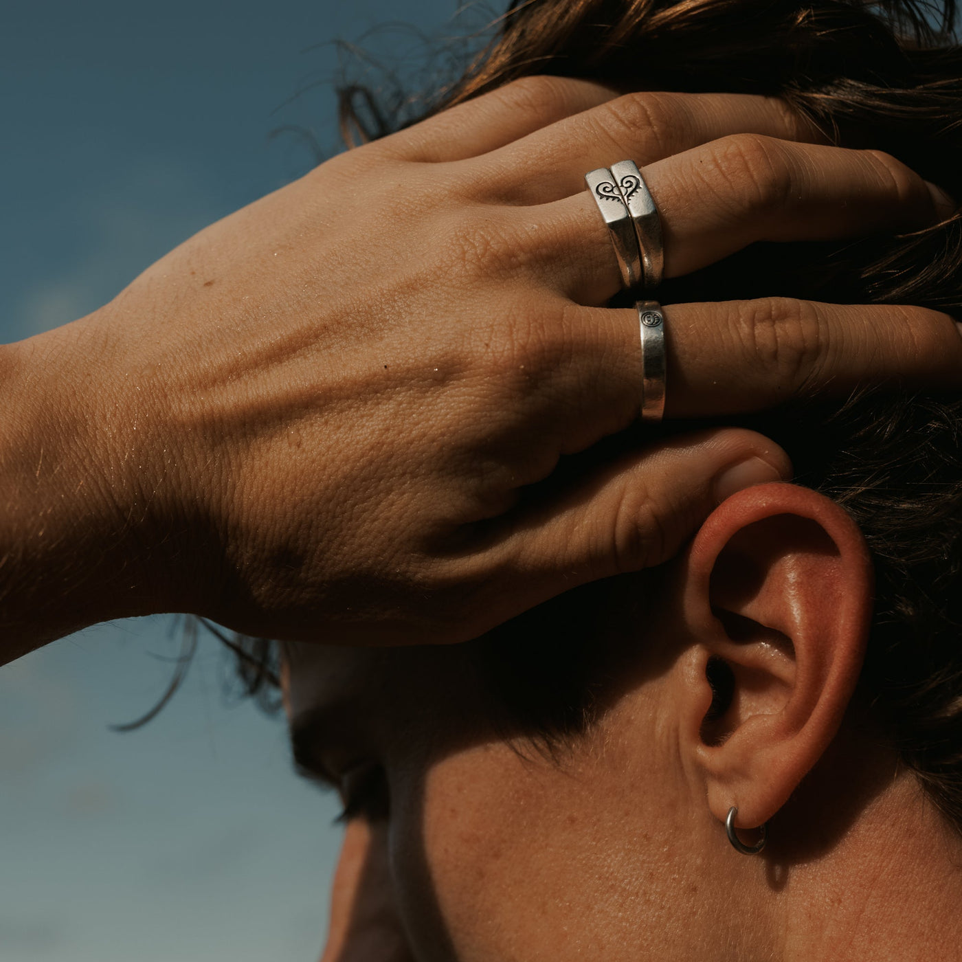A man wearing the Billie Jo Connection Stackers rings, running his hand through his hair outdoors. Men's jewellery styling inspiration from Australia.