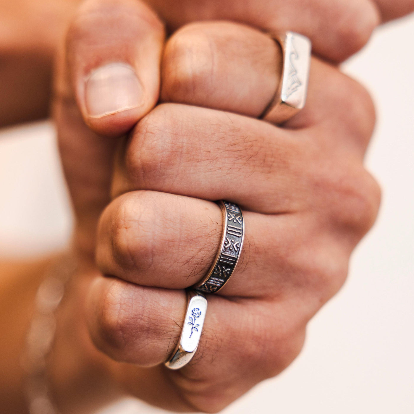 A close-up shot of a model's fist with multiple rings, including the ROSA I RING, highlighting the masculine and modern style of Billie Jo jewellery.