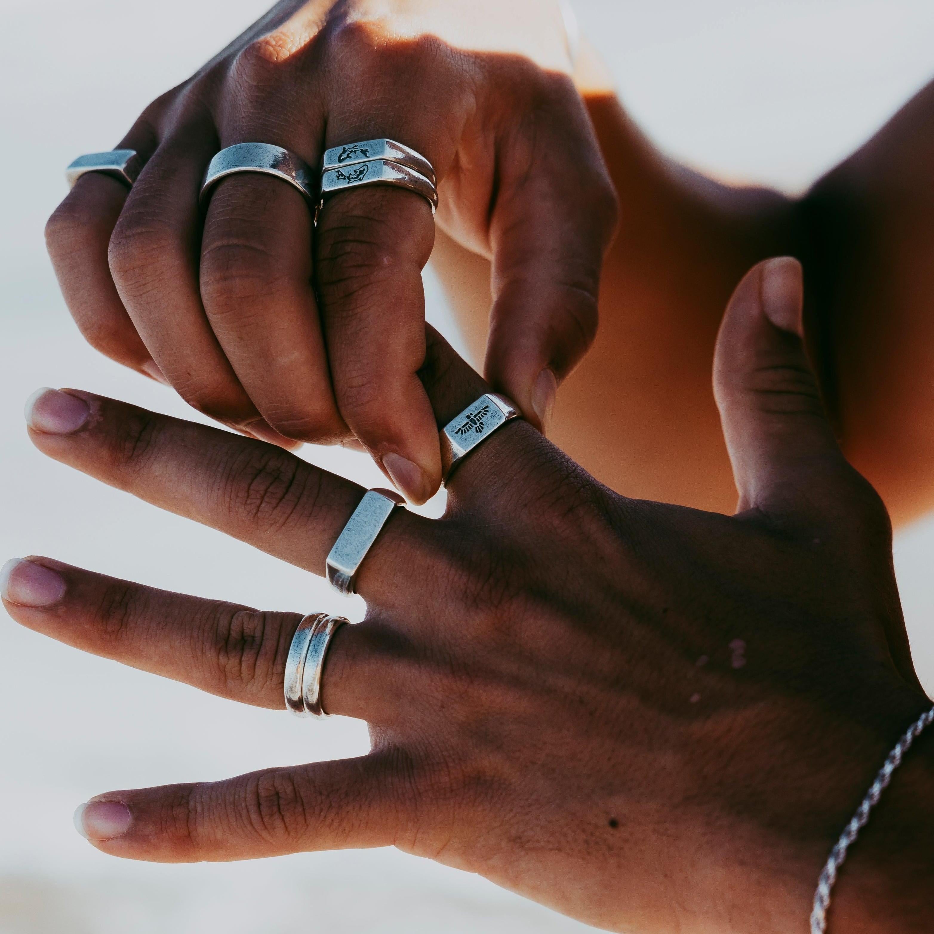 A man with a medium skin tone adjusts the sterling silver Elation Ring on his finger. He wears other silver rings from Australian brand Billie Jo.