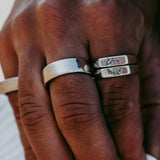 A close-up of a hand wearing three silver billie jo rings, two of which have engraved designs. The skin tone is medium, and the background is softly blurred. v1