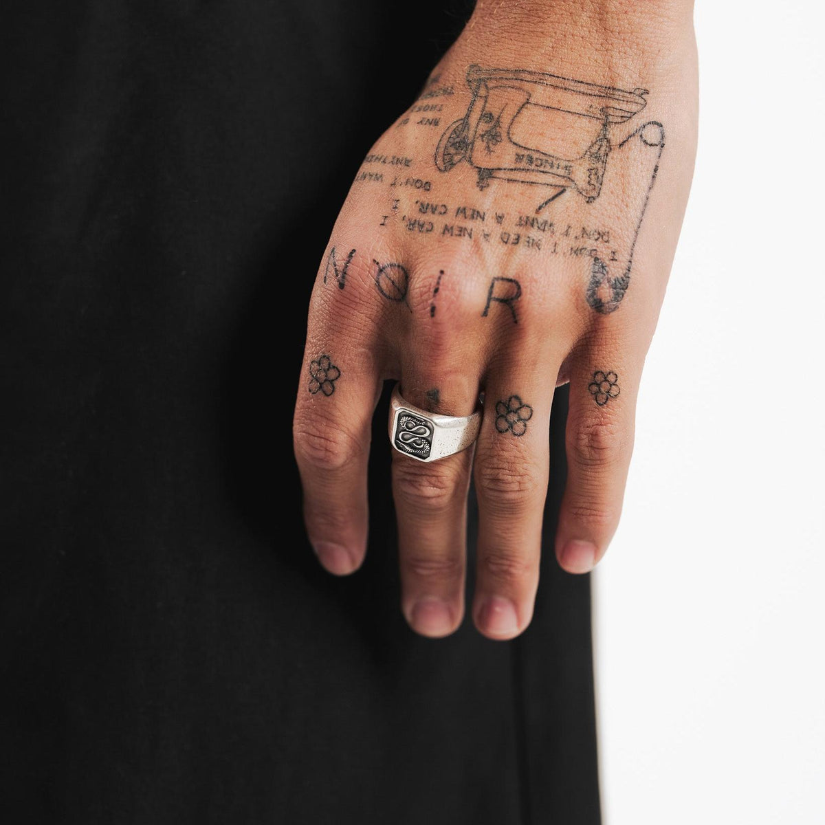 The Billie Jo Serpent Ring worn on the hand of a man with intricate tattoos, showcasing its bold and edgy style against a dark backdrop.