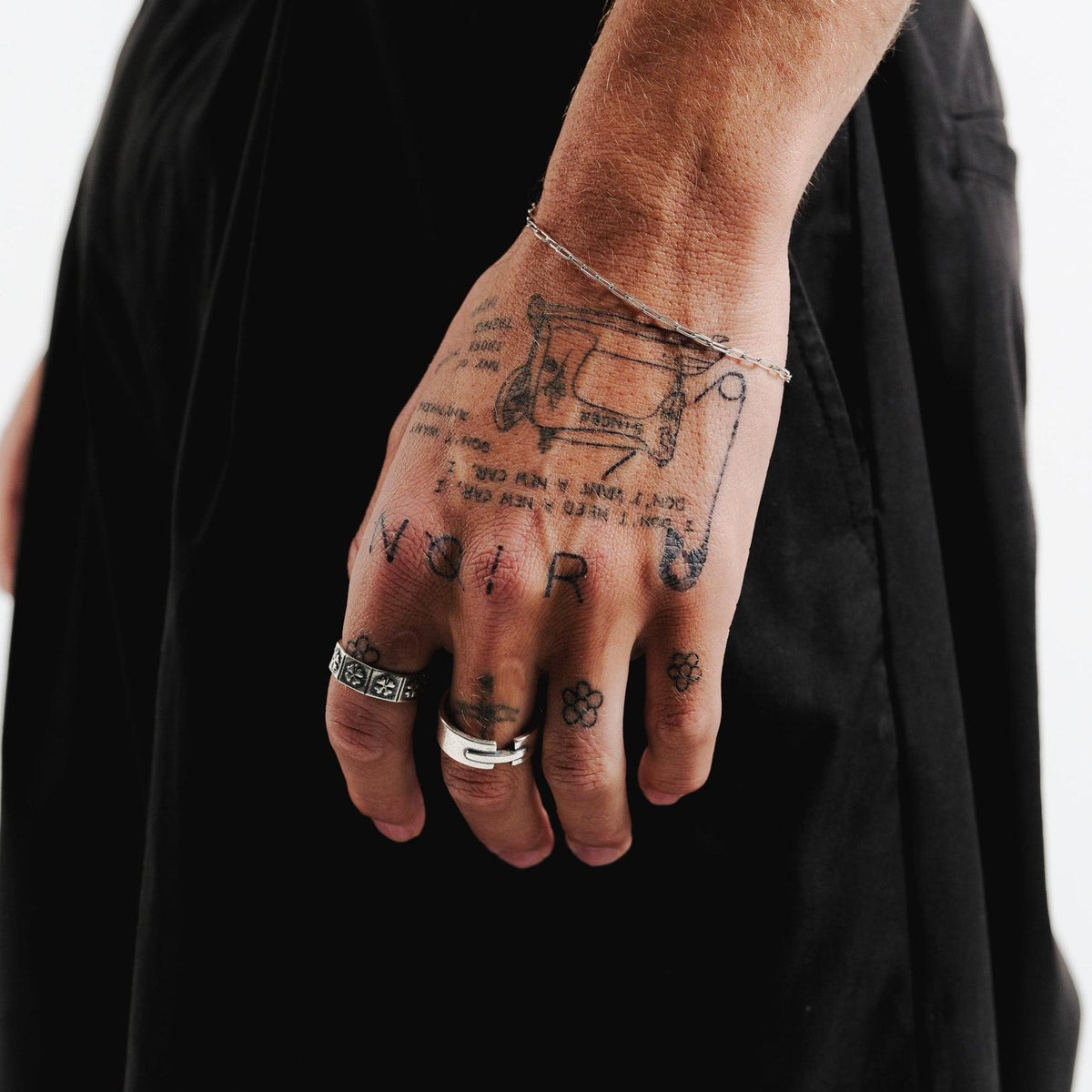 A man with hand tattoos wears the sterling silver Billie Jo LUCKY RING on his index finger, complemented by a simple silver bracelet.