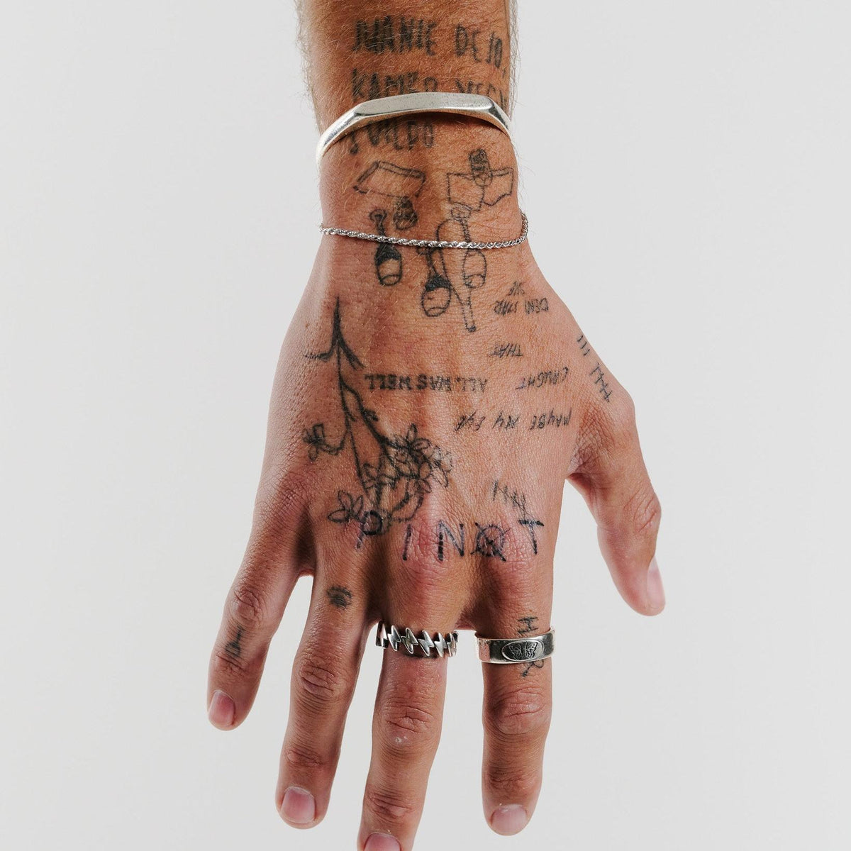 A detailed on-hand shot of the Slim Rope Bracelet from Billie Jo, layered with a silver cuff on a tattooed arm for a stacked, modern aesthetic.