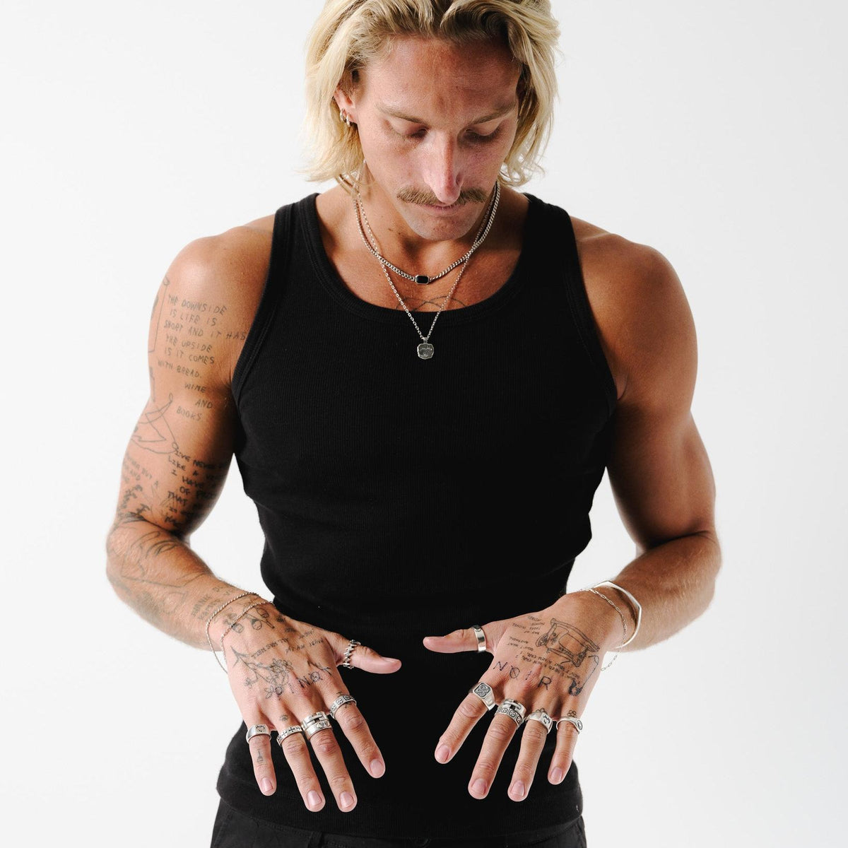 A model with tattoos wears the Billie Jo Eclipse Necklace layered with other silver chains, showcasing a modern, masculine jewellery look.
