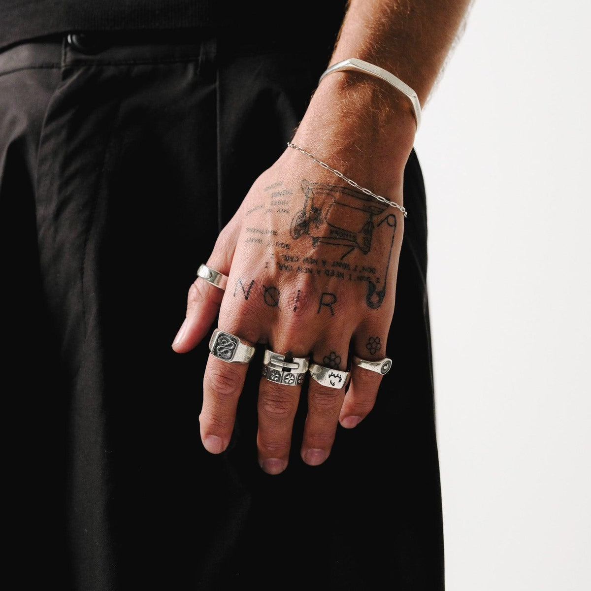 A sterling silver cuff and the Slim Link Bracelet from Billie Jo, an Australian men’s jewellery brand, styled on a tattooed wrist for a modern look.