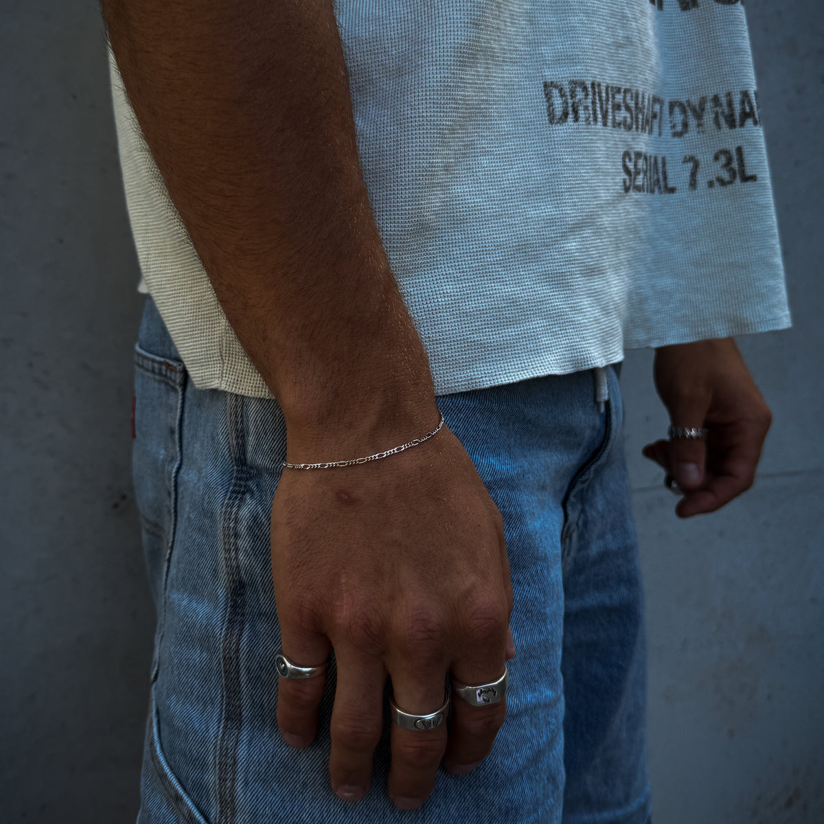 A man wearing the sterling silver Slim Figaro Bracelet from Billie Jo. This lifestyle image shows the bracelet paired with casual denim and a graphic tee, highlighting its versatile, everyday style for men.