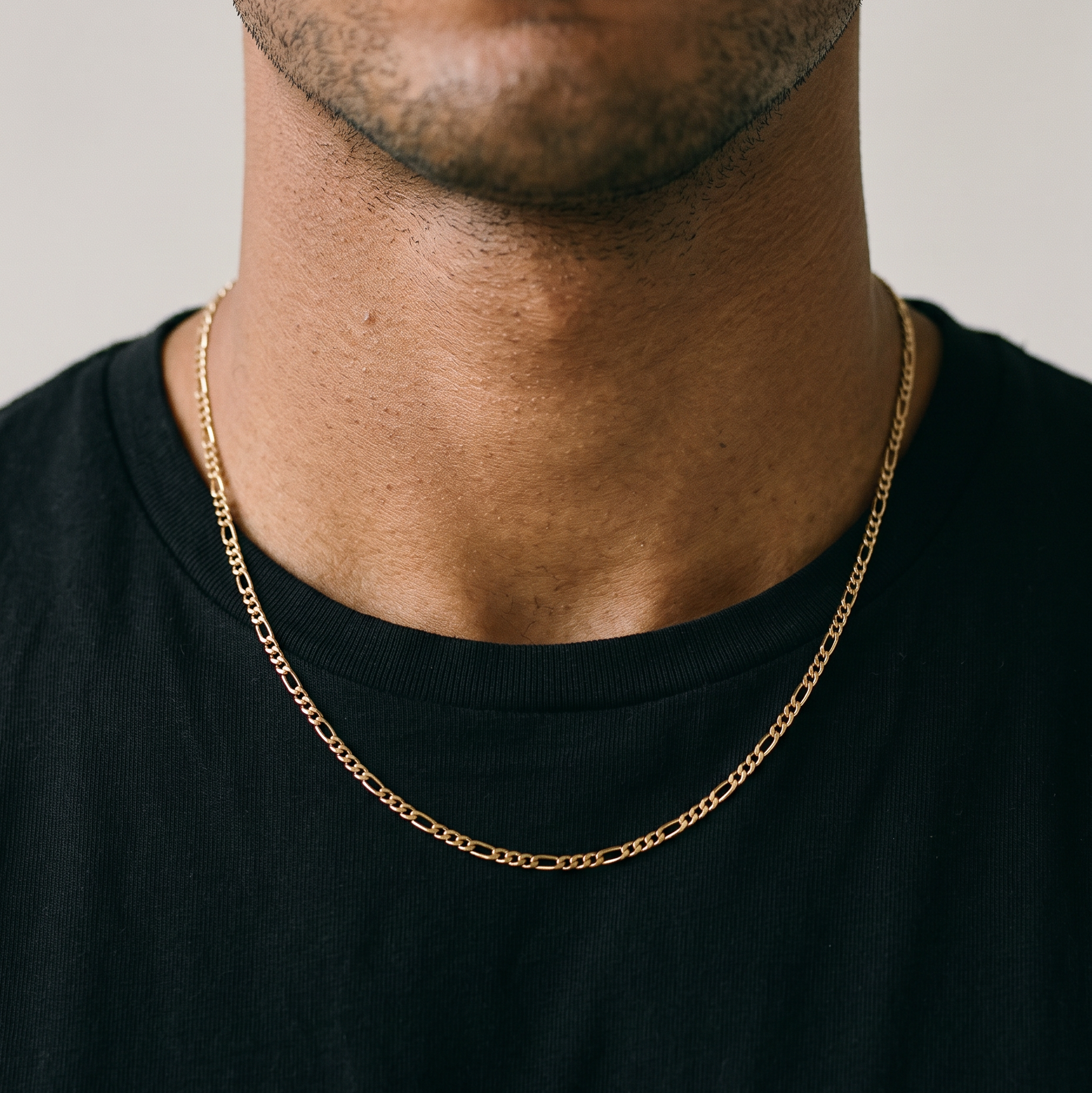 A male model wearing a gold tone stainless steel slim Figaro chain necklace from Australian jewellery brand Billie Jo