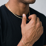 A male model wearing a gold tone stainless steel slim Figaro chain necklace from Australian jewellery brand Billie Jo