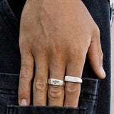 A man's hand resting on the back pocket of black denim jeans, wearing the Elation Ring and another silver ring from Australian jewellery brand Billie Jo.
