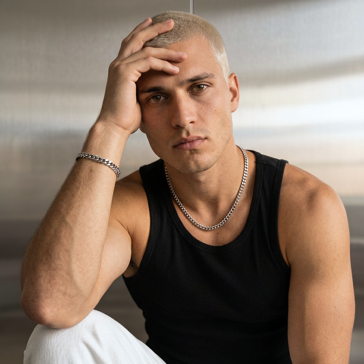 A male model wearing a silver stainless steel slim Figaro chain necklace from Australian jewellery brand Billie Jo, shot against a sleek silver chrome background. 