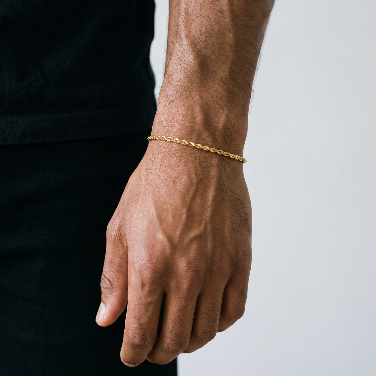 A gold tone stainless steel slim rope chain bracelet from Australian jewellery brand Billie Jo, worn by a male model against a warm gold backdrop, a waterproof sweat proof everyday necklace and the perfect gift for him.