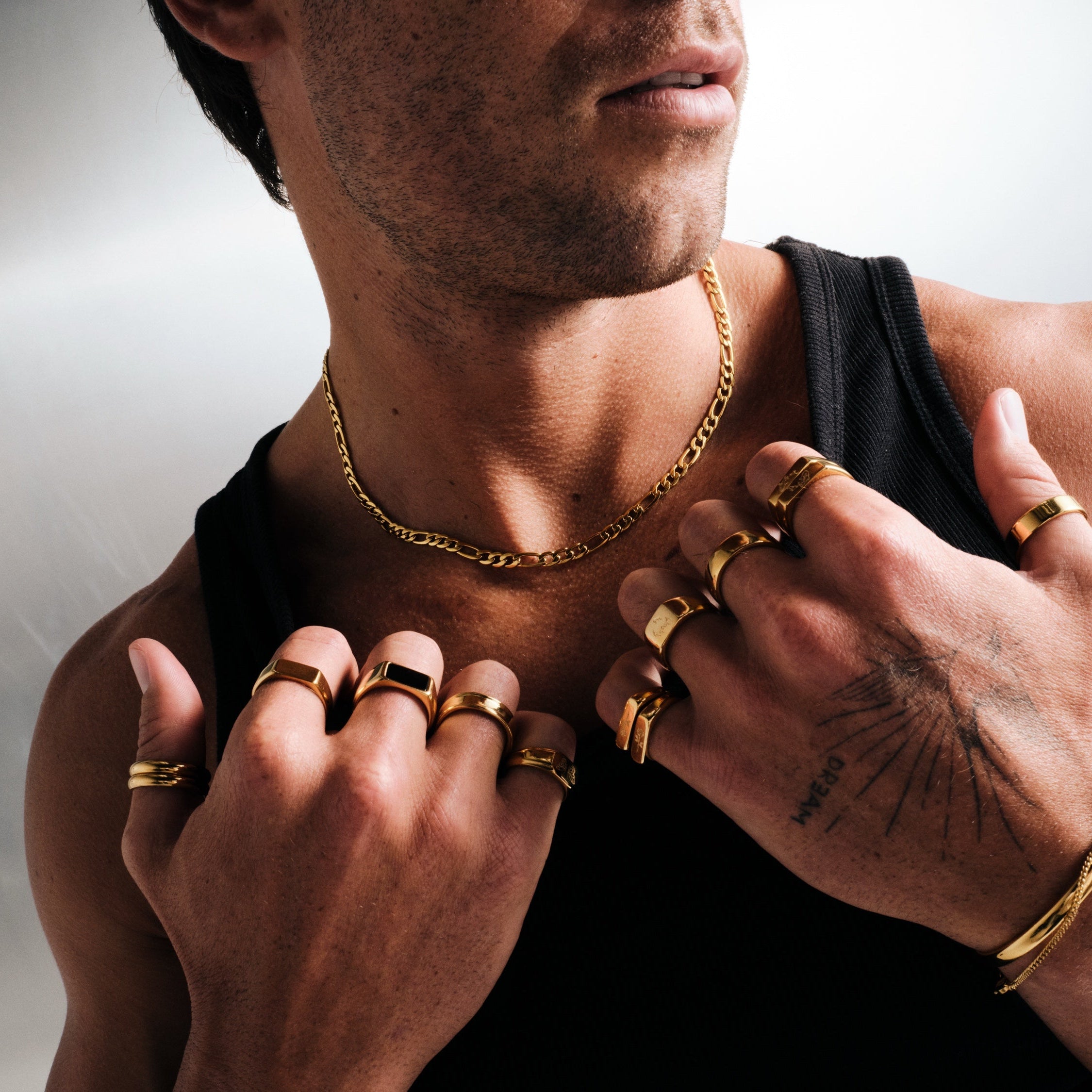 Men's Gold Genesis Ring in 18k gold infused stainless steel, worn on the index finger, hands held to his chest, black singlet
