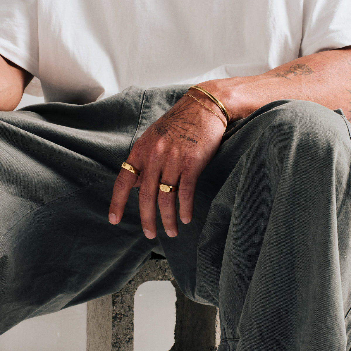 Men's Gold Genesis Ring in 18k gold infused stainless steel, worn on his left index finger, white tee, olive pants