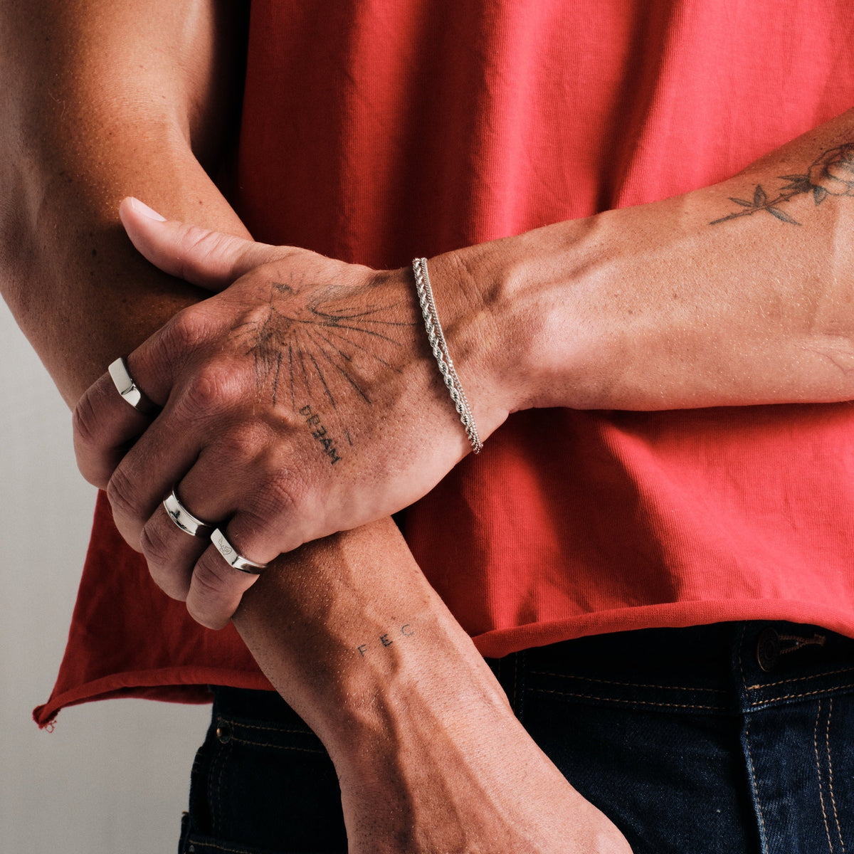 Men's Genesis Ring in 316L stainless steel, silver finish, worn on the index finger, left hand gripping right forearm
