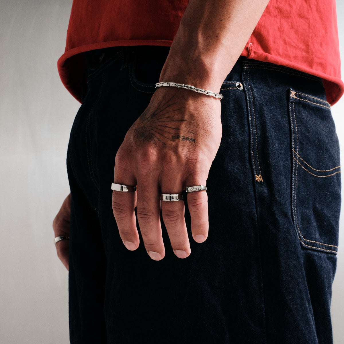 Men's Genesis Ring in 316L stainless steel, silver finish, worn on the index finger, hand by his back pocket