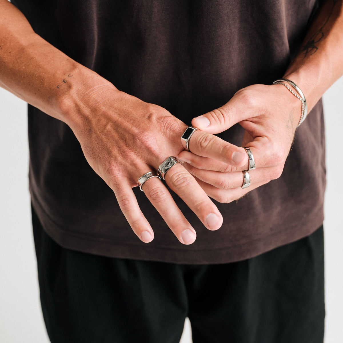 Men's Koi Stackers in 316L stainless steel, silver finish, both worn on his right middle finger, brown tee, black pants