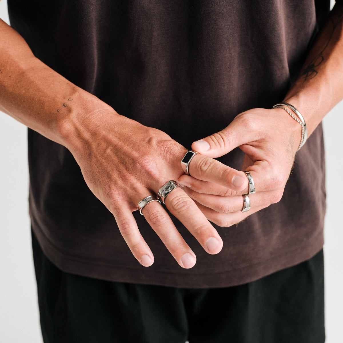 Men's Onyx Ring in 316L stainless steel, silver finish, worn on his right index finger, hands together at the waist