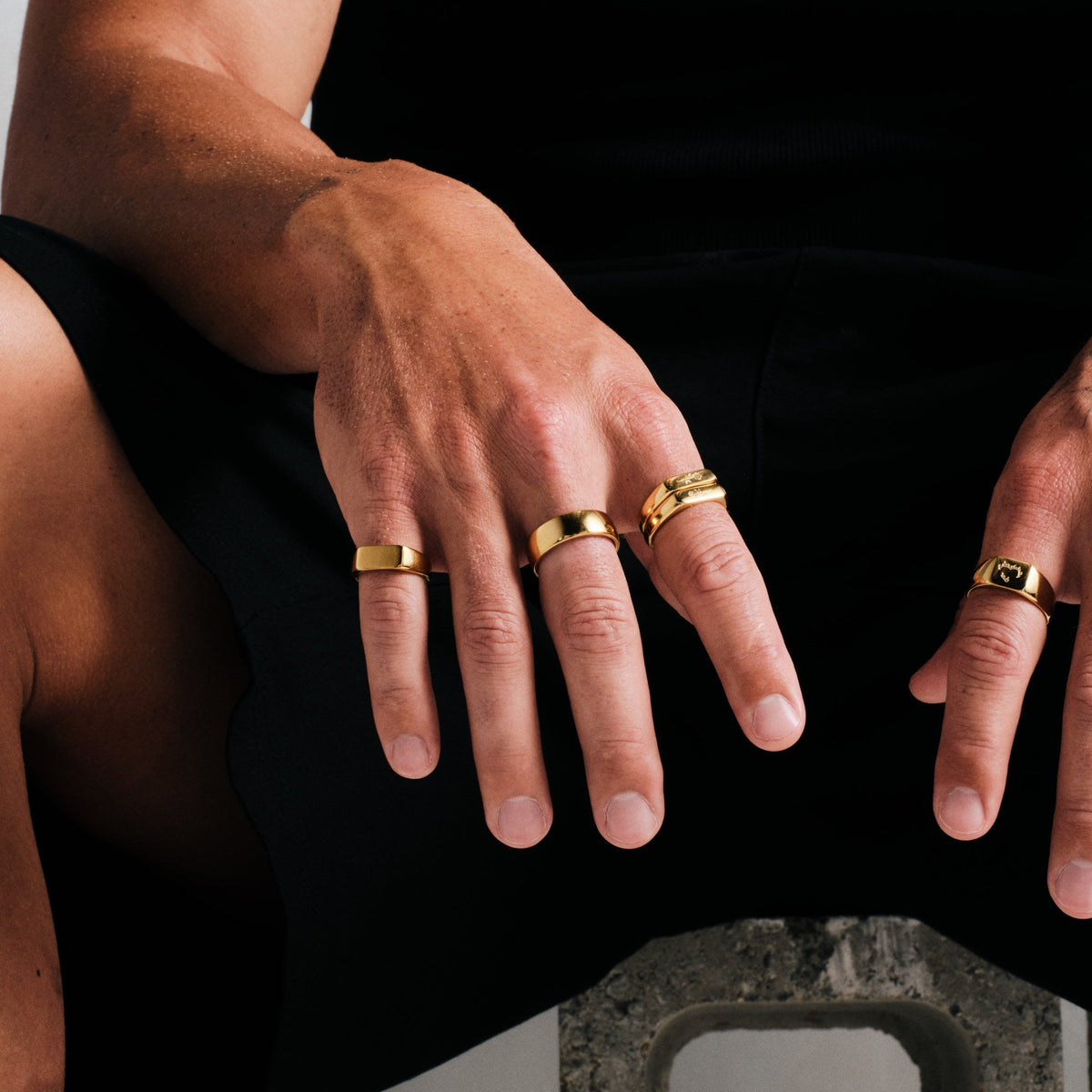 Men's Gold Rosa Stackers in 18k gold infused stainless steel, worn on the index finger, black singlet, black shorts