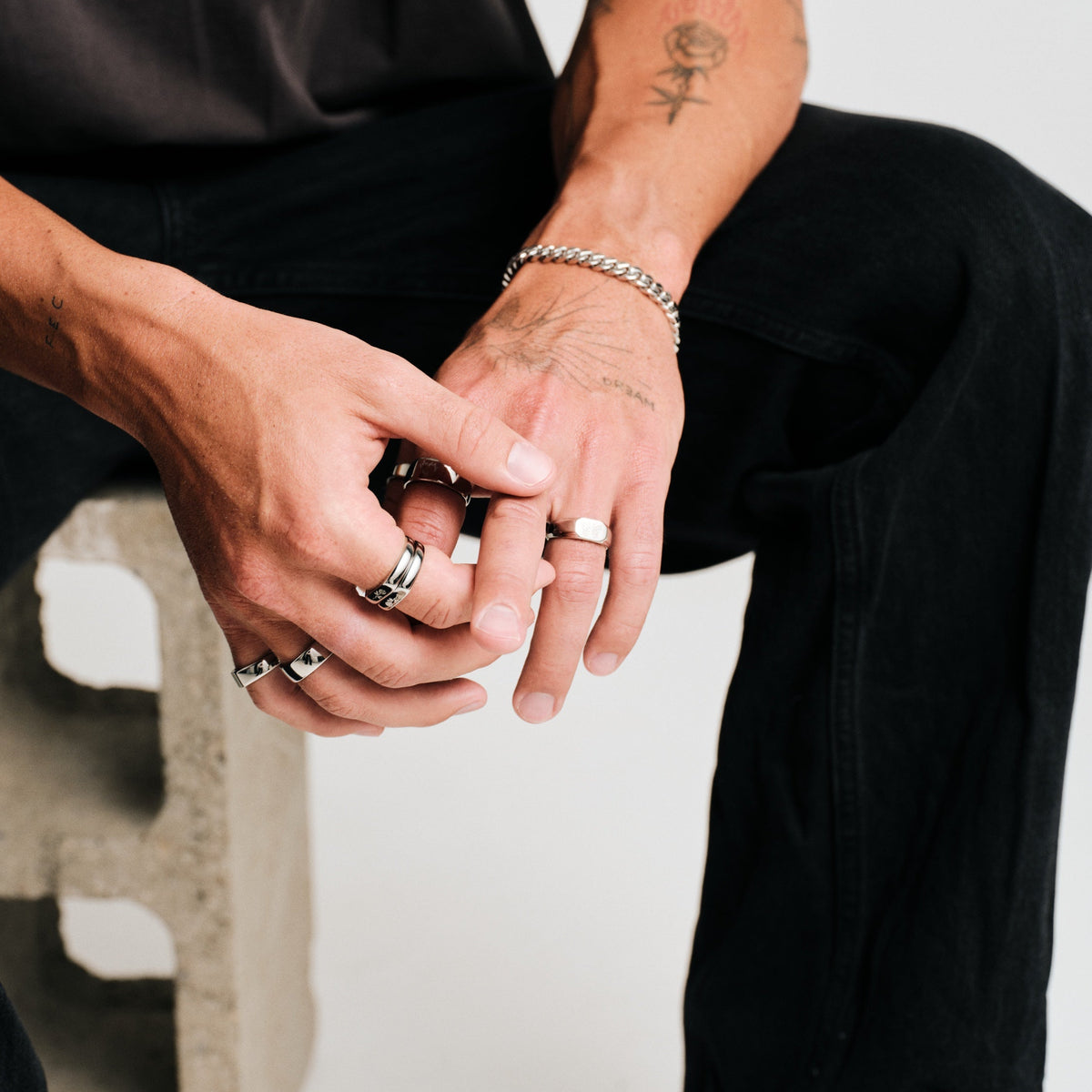 Men's Rosa Stackers in 316L stainless steel, silver finish, worn on the middle finger, black tee, black jeans