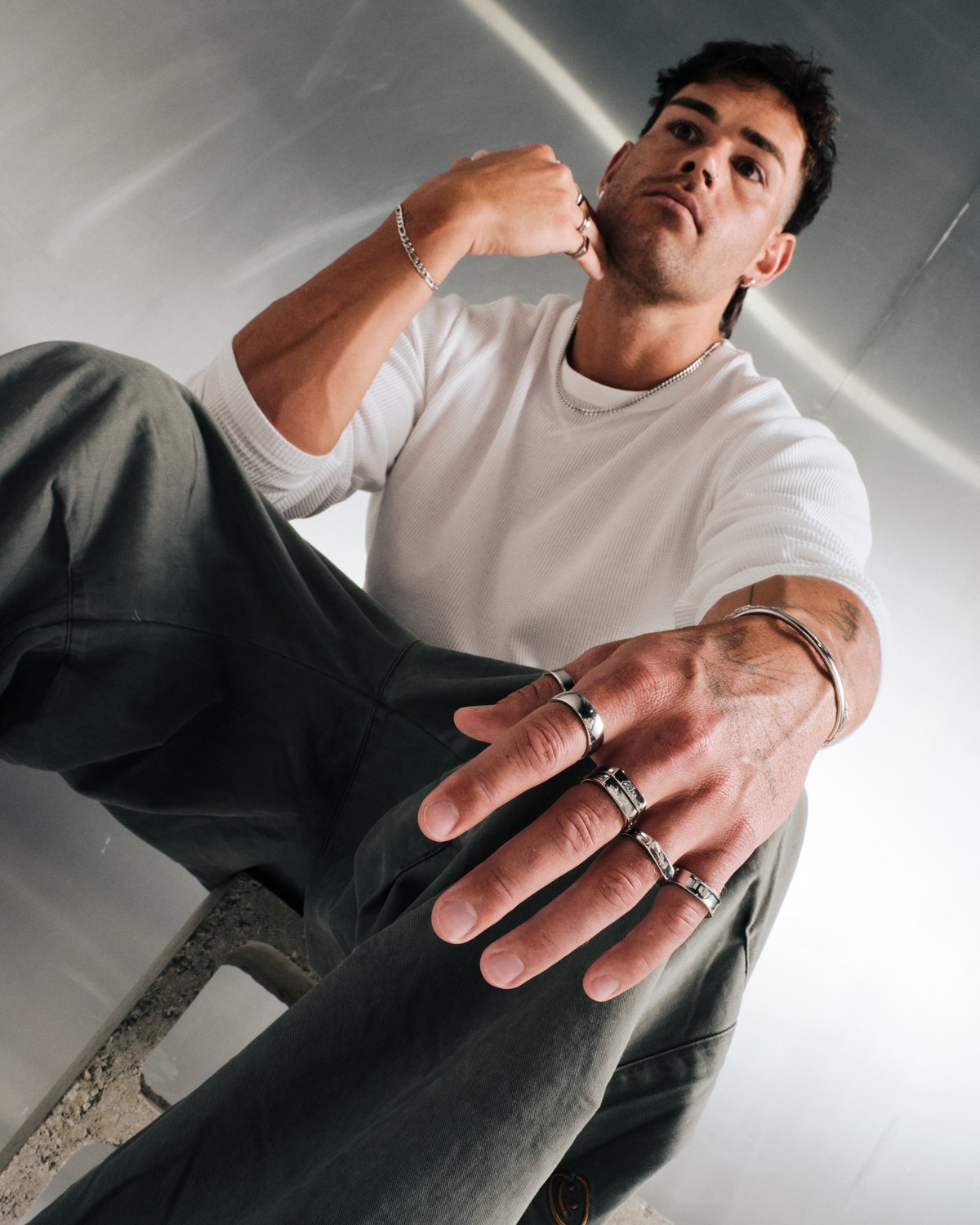 Low angle shot of a man wearing silver stainless rings and a cuff